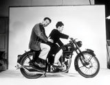  Charles and Ray Eames pose on a Velocette motorcycle, 1948. © Eames Office, LLC.